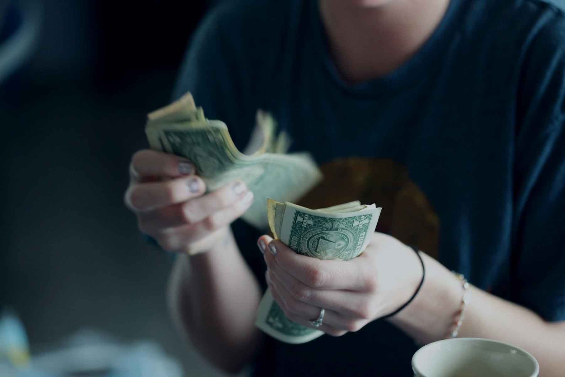 A person counting money, symbolizing the cost and investment of portable power stations, with a blurred background emphasizing financial considerations.