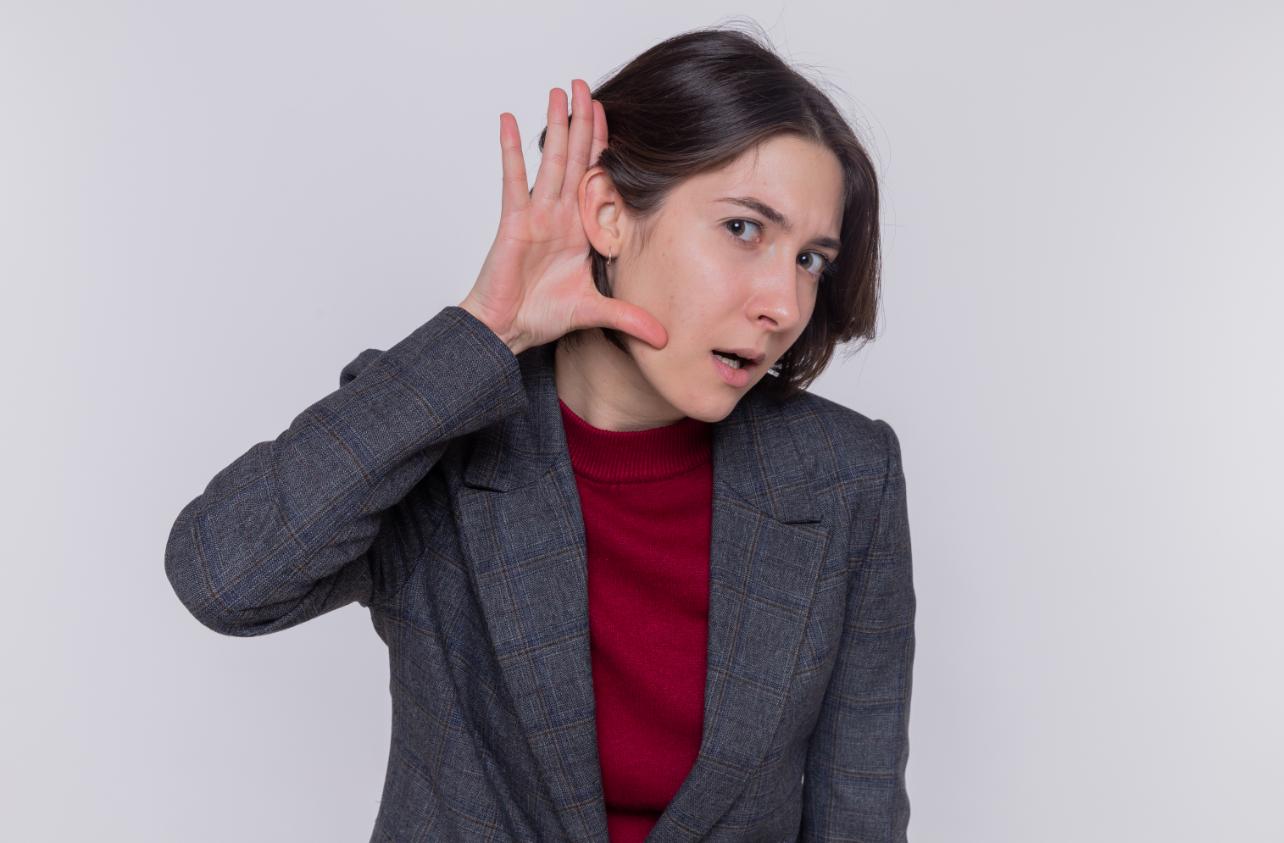 A woman cupping her ear, appearing to listen intently, symbolizing curiosity about noise levels, relating to whether portable power stations are noisy.