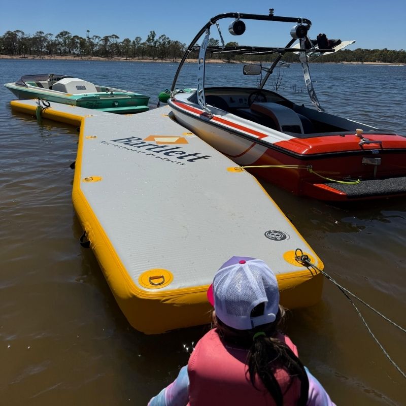 Bartlett Y-shaped inflatable pontoon used for boat docking during daytime with a child observing