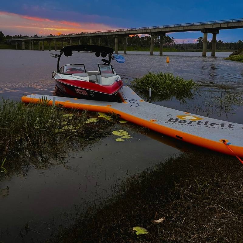 Bartlett Y-shaped inflatable pontoon docked at sunset near a river with a bridge in the background