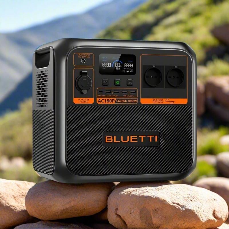 Bluetti AC180P portable power station sitting on rocks with scenic mountain background and natural sunlight