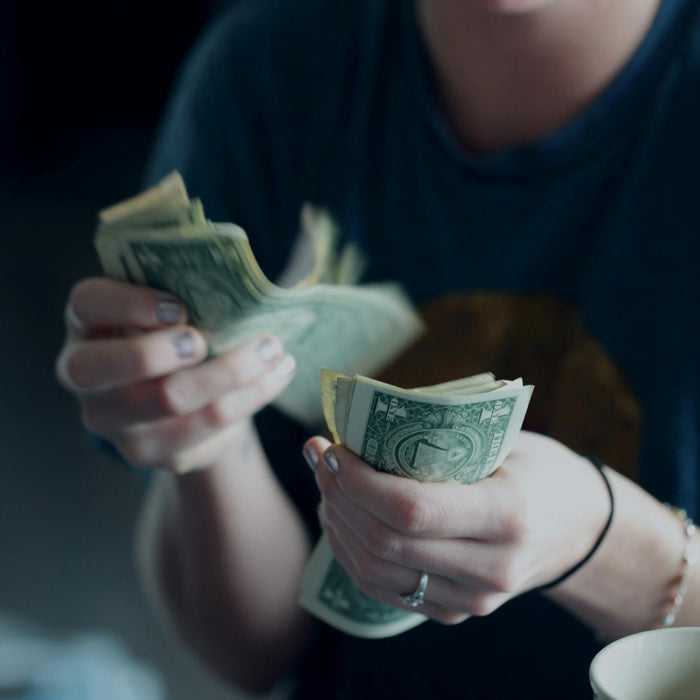 A person counting money, symbolizing the cost and investment of portable power stations, with a blurred background emphasizing financial considerations.