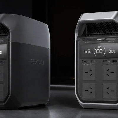 Side-by-side comparison of two EcoFlow portable power stations, one dark gray and one silver, in a professional studio setup, showing design differences and digital screens, with soft directional lighting and subtle reflections.