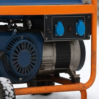 Portable generator with an orange frame sitting in the snow during winter.