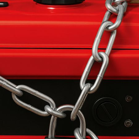 Red portable generator secured with a heavy-duty chain and padlock, photographed as a wide cover image against a wooden backdrop.