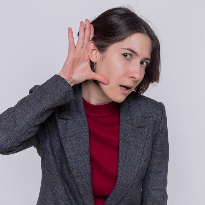 A woman cupping her ear, appearing to listen intently, symbolizing curiosity about noise levels, relating to whether portable power stations are noisy.