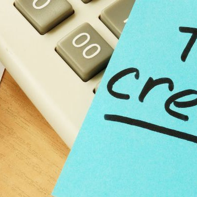 A calculator, tax documents, and a note reading "Tax Credits," representing potential tax benefits and deductions for portable power stations in Australia.