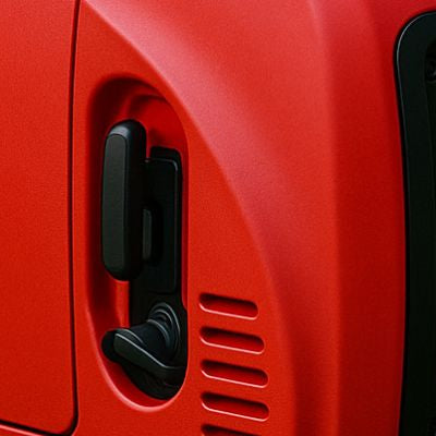 Red portable inverter generator placed on green grass in a peaceful outdoor setting.