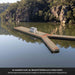 Harbour Y 8.5 Grain floating on a calm river below sandstone cliffs with an esky on the deck