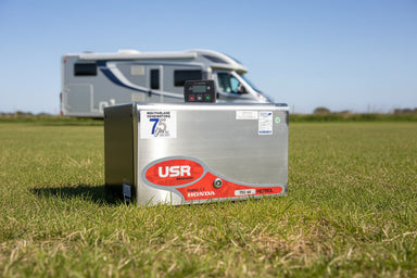 USR petrol inverter generator on an open field with a recreational vehicle in the background.