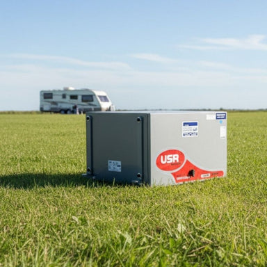 Portable generator lying on an open field and a caravan in the background.