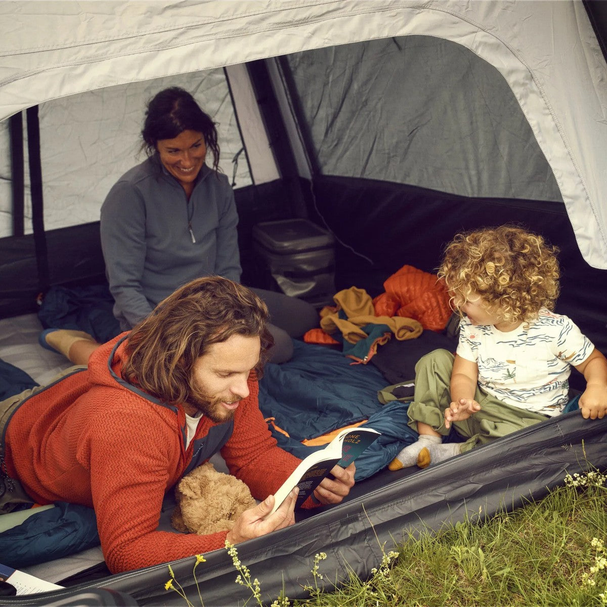 Dad and two kids lying inside the Reunion tent reading together
