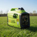 Green and black portable generator on grass with a clear sky