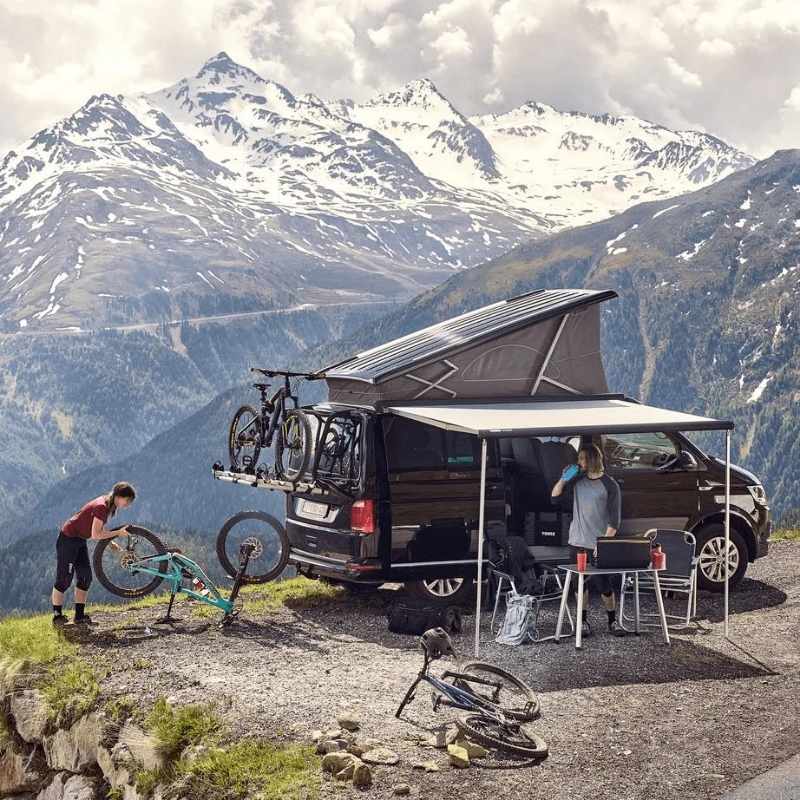 Thule 4200 Awning Manual Cassette mounted on compact van with bikes and mountain backdrop.