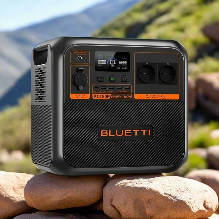 Bluetti AC180P portable power station sitting on rocks with scenic mountain background and natural sunlight
