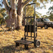 Black Bluetti Foldable Trolley 2 on a dry grass campsite under a gum tree with a camp chair and a 4WD behind it