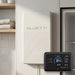 Bluetti FridgePower mounted on a laundry wall beside a fridge, with the Display 1 magnetic screen showing charge and power readings
