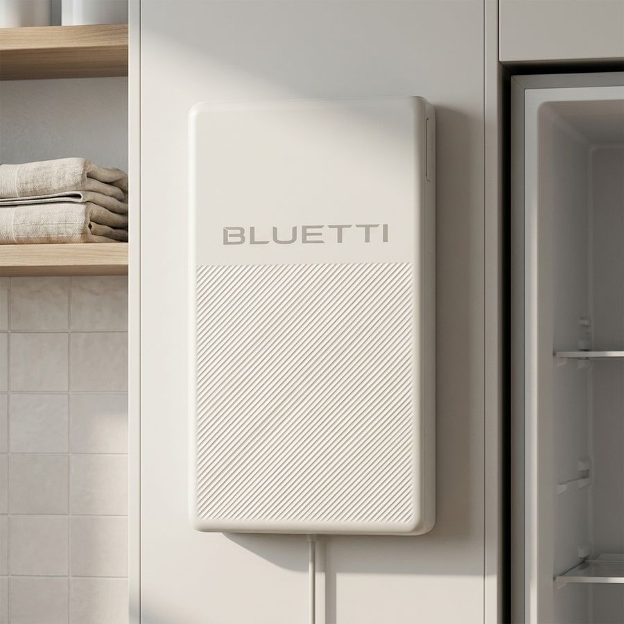 Bluetti FridgePower mounted flat against a laundry wall beside a fridge, power cable running down