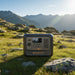 Bluetti Premium 100 V2 portable power station on grass in the mountains providing clean off-grid energy for outdoor adventures.