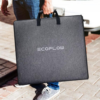 Man holding foldable solar panel kit on suburban pavement
