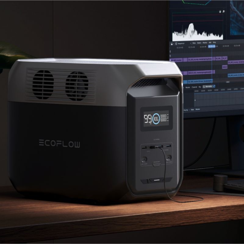 Portable power station charging devices at a desk next to a monitor.
