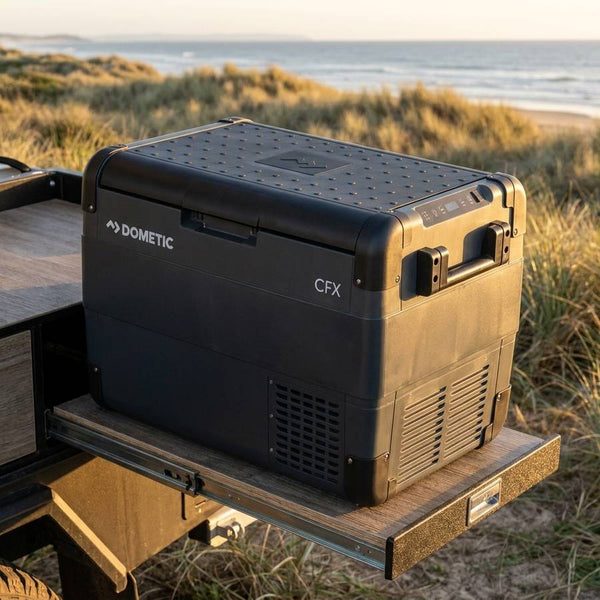 Dometic CFX2 57 portable fridge freezer on a camper trailer slide-out kitchen on a coastal dune track at sunset