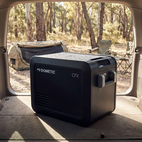 Dometic CFX5 25 portable fridge freezer in the open rear of a station wagon at a bush campsite in early morning light