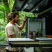 Camper reaching into a Dometic NRX 80C fridge fitted in a 4WD canopy in rainforest