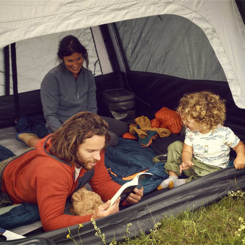 Family lying on a mattress inside the Dometic Reunion FTG 5x5 Redux reading a book