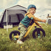 Child on a balance bike in front of a pitched Dometic Reunion FTG 5x5 Redux on open grass