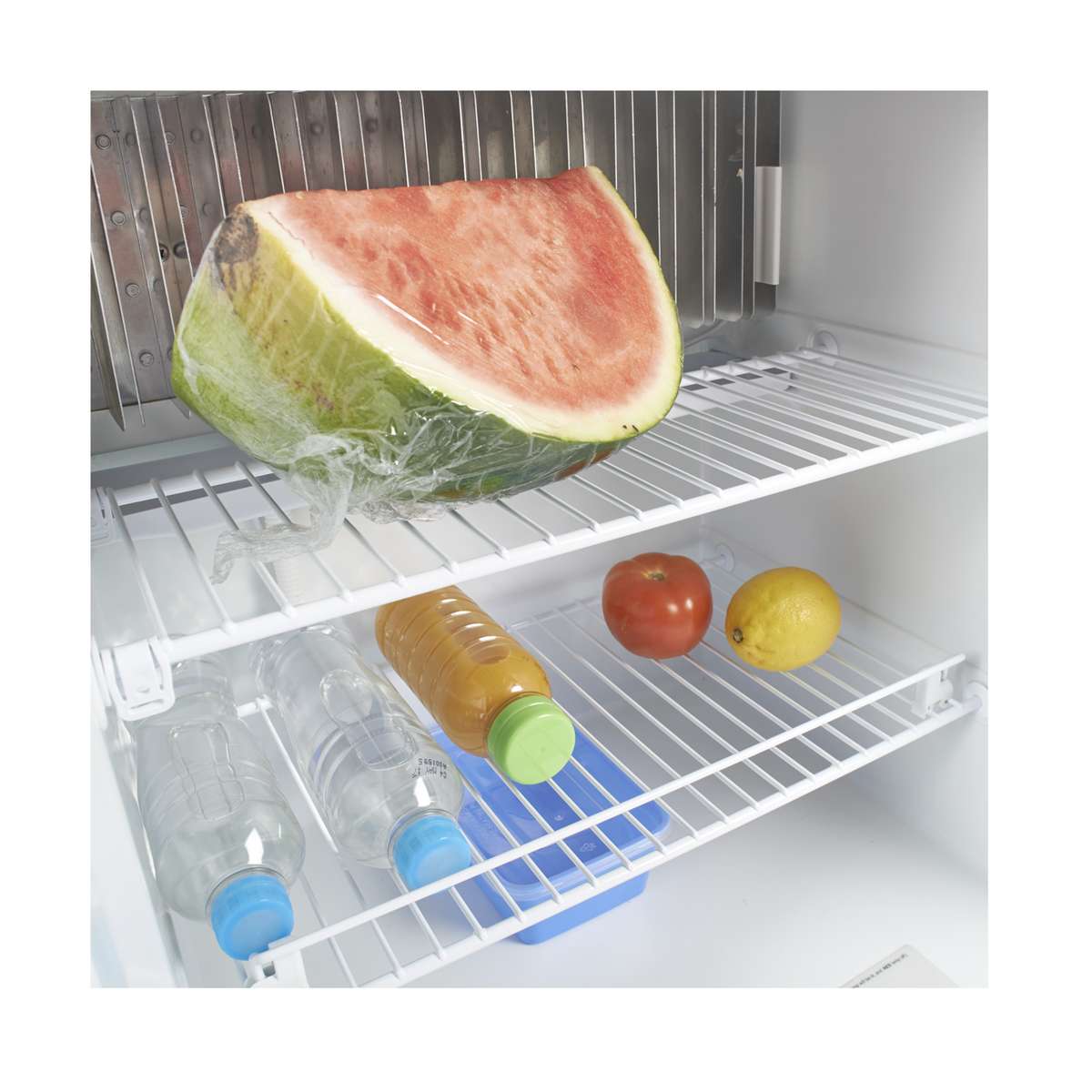 Wire shelf inside the Dometic RM 2350 holding a cut watermelon, drinks and fruit