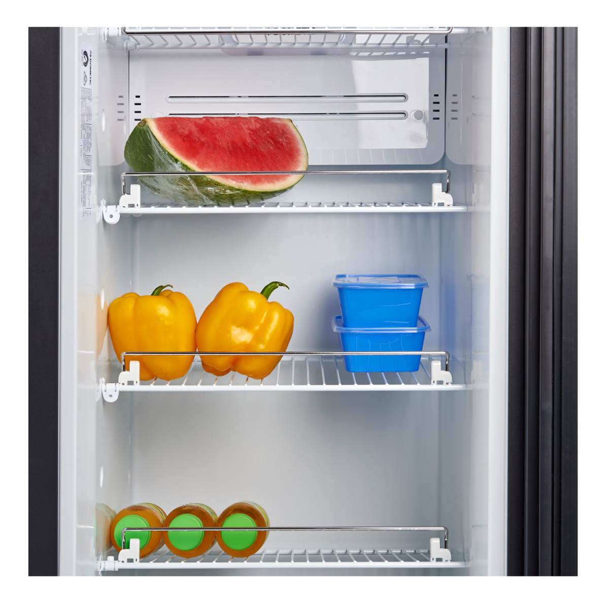 Stocked fridge shelves inside a Dometic RUC 8408X holding watermelon, capsicums and storage containers