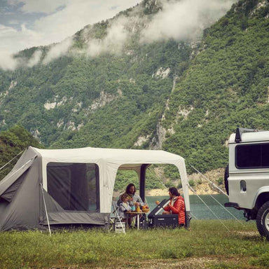 Dometic Santorini FTK 2x4 TC pitched beside a 4WD on a lakeside flat with a family eating under the canopy