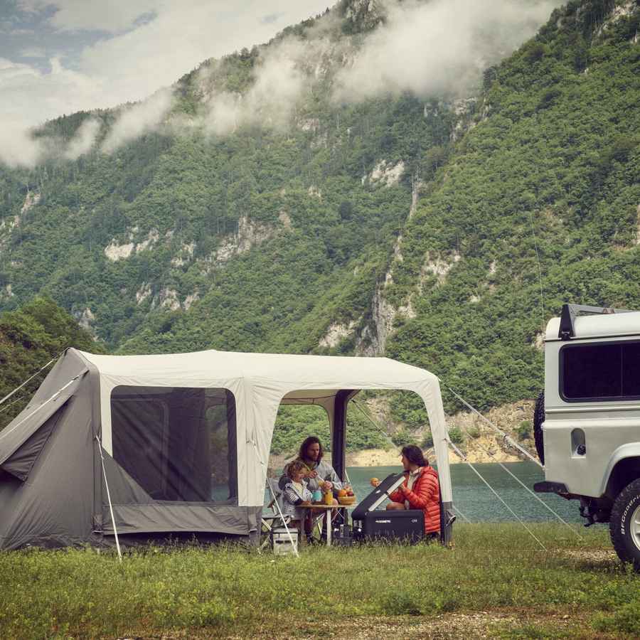 Dometic Santorini FTK 2x4 TC pitched beside a 4WD on a lakeside flat with a family eating under the canopy