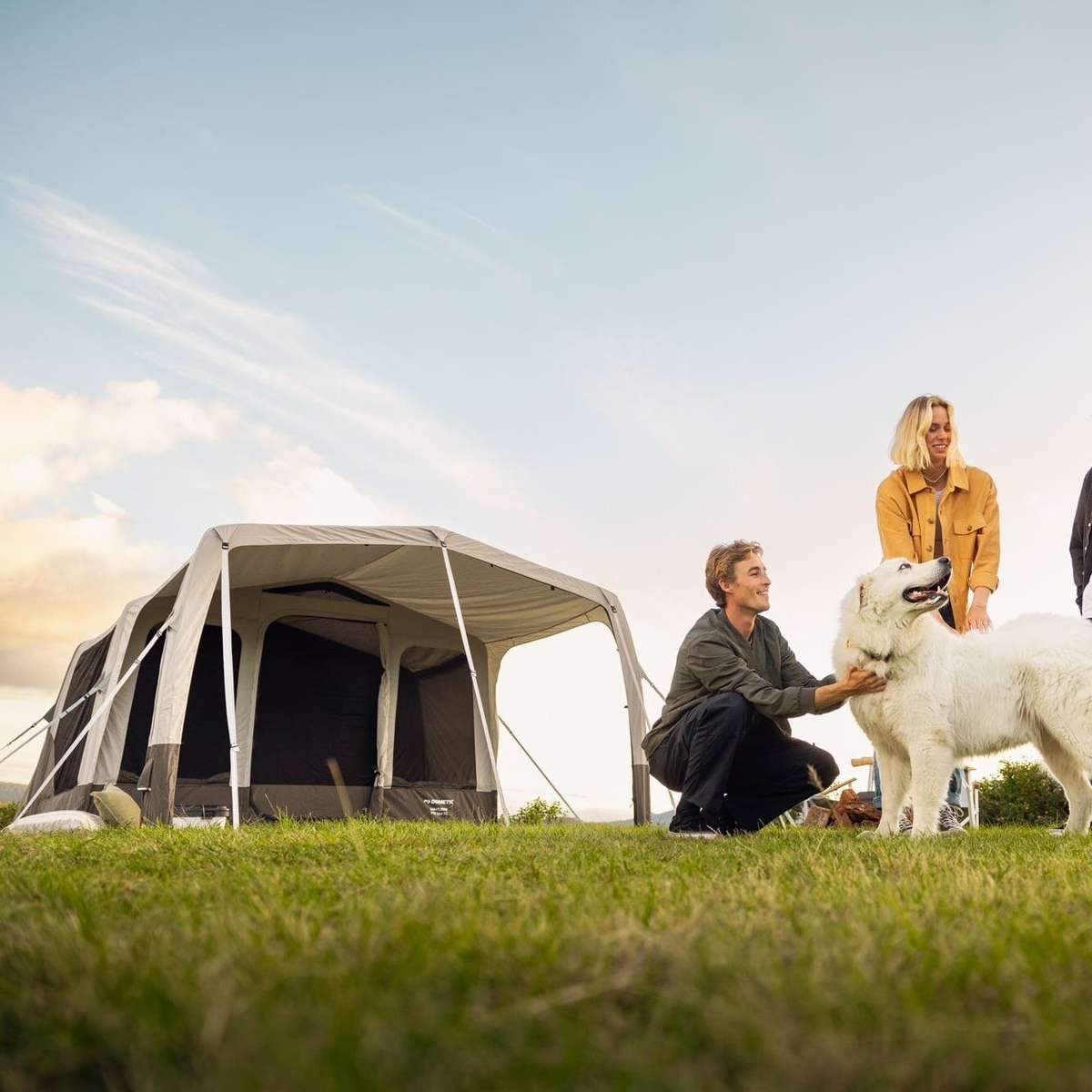 Dometic Santorini FTK 2x4 TC pitched on a grassy headland with a group and a dog beside the canopy