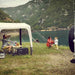 Camp set up under the Dometic Santorini FTK 4x8 TC canopy with a table, chairs and a fridge beside a lake