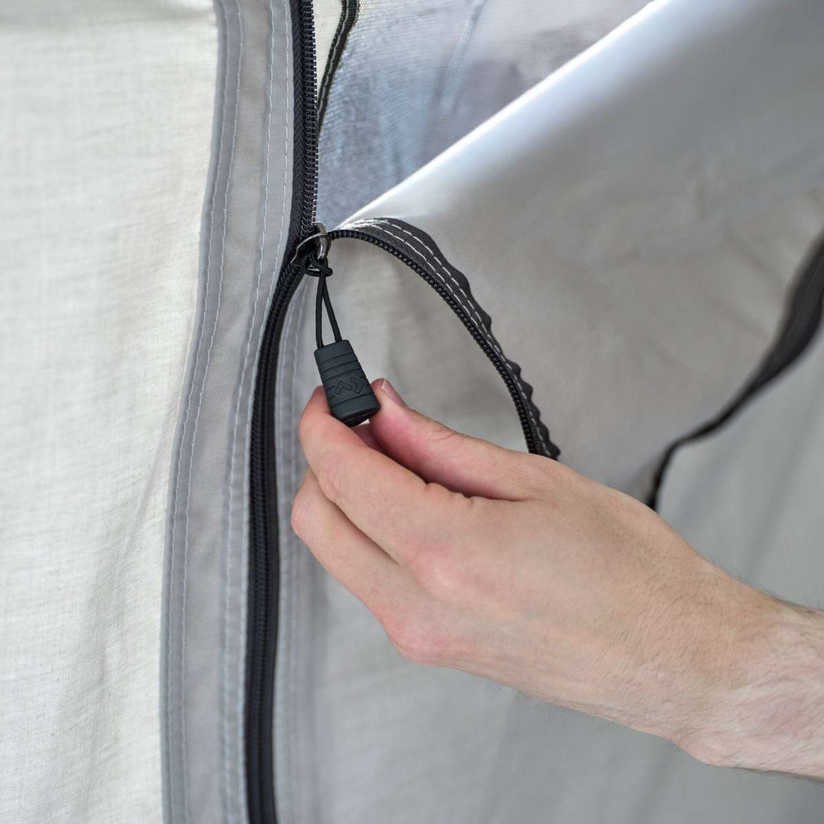 Close-up of a hand pulling the zip along the edge of the front door panel