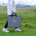 A woman walking outdoors carrying the EcoFlow 110W Solar Panel in grey case