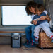 Two kids sitting in a camper while their game device charges from a power unit.