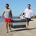 MyCOOLMAN 85L fridge freezer being carried on the beach by two men