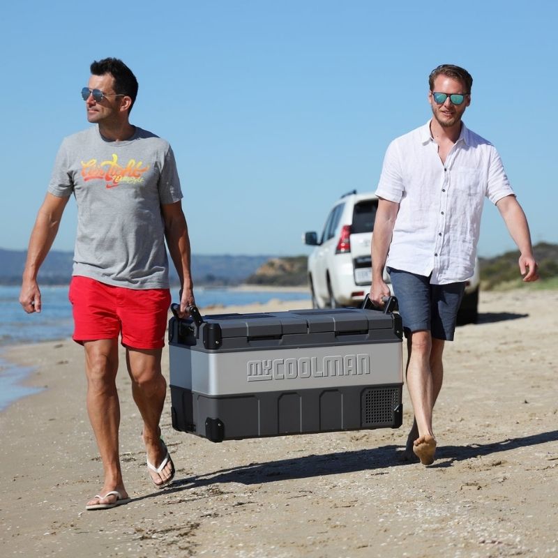 MyCOOLMAN 85L fridge freezer being carried on the beach by two men