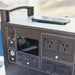 Front panel of the myCOOLMAN 1920Wh power station on a folding table with a phone charging beside it