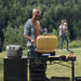 Man grilling while using a portable power station at an outdoor campsite.