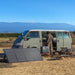 A man camping off-grid with solar panel and Bluetti power station next to a van in the mountains