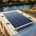 Renogy 100W N-type solar panel flat-mounted on a small camper trailer roof beside a river