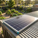 Renogy 100W N-type solar panel mounted on a garden shed roof above a suburban vegetable garden