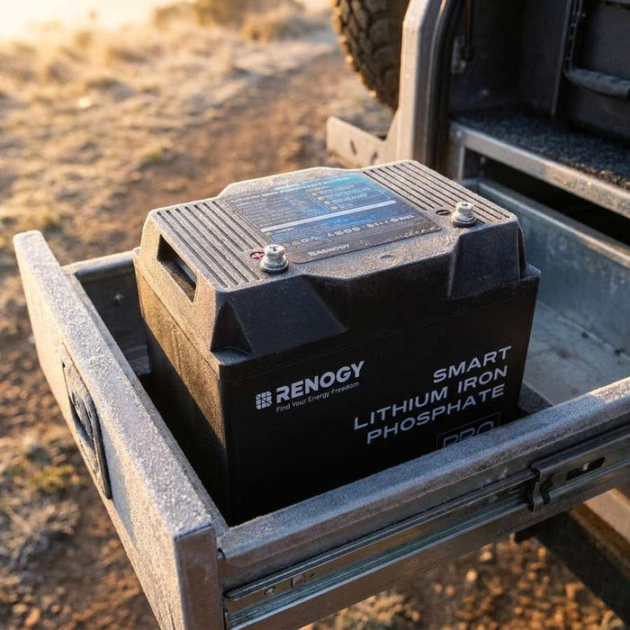 Renogy Pro 100Ah battery mid-install in an open battery box in a 4WD canopy drawer, light frost on the tray at first light