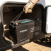 Renogy 12V 200Ah battery lifted by its rope handle from an open caravan storage locker