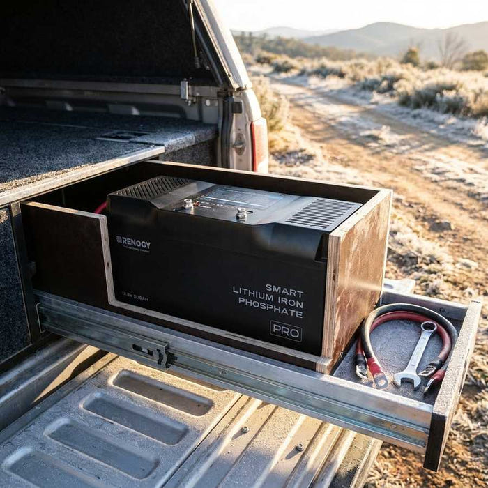 Renogy Pro 200Ah battery mid-install in an open battery box in a 4WD canopy drawer, light frost on the tailgate at first light