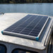 Renogy 175W N-Type solar panel mounted on a small aluminium boat cabin roof beside a calm inland lake